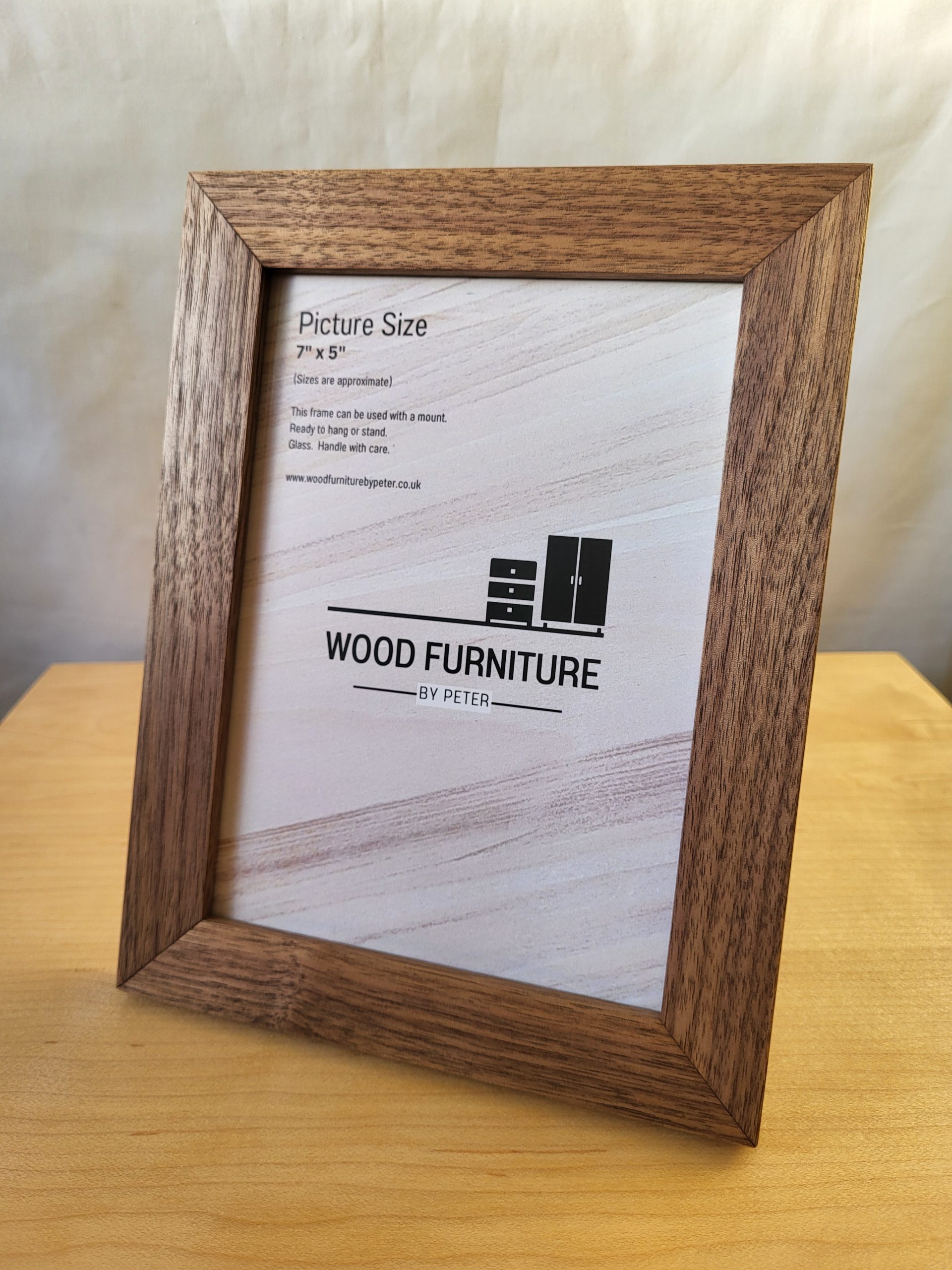 Handcrafted wooden picture frame by Wood Furniture by Peter, displayed on a light wood surface. Rich brown finish with visible grain detail. Frame insert features brand logo and text: “WOOD FURNITURE BY PETER – Picture Size 7" x 9" (18 x 23 cm)”. Artisan-made, ideal for showcasing cherished memories.