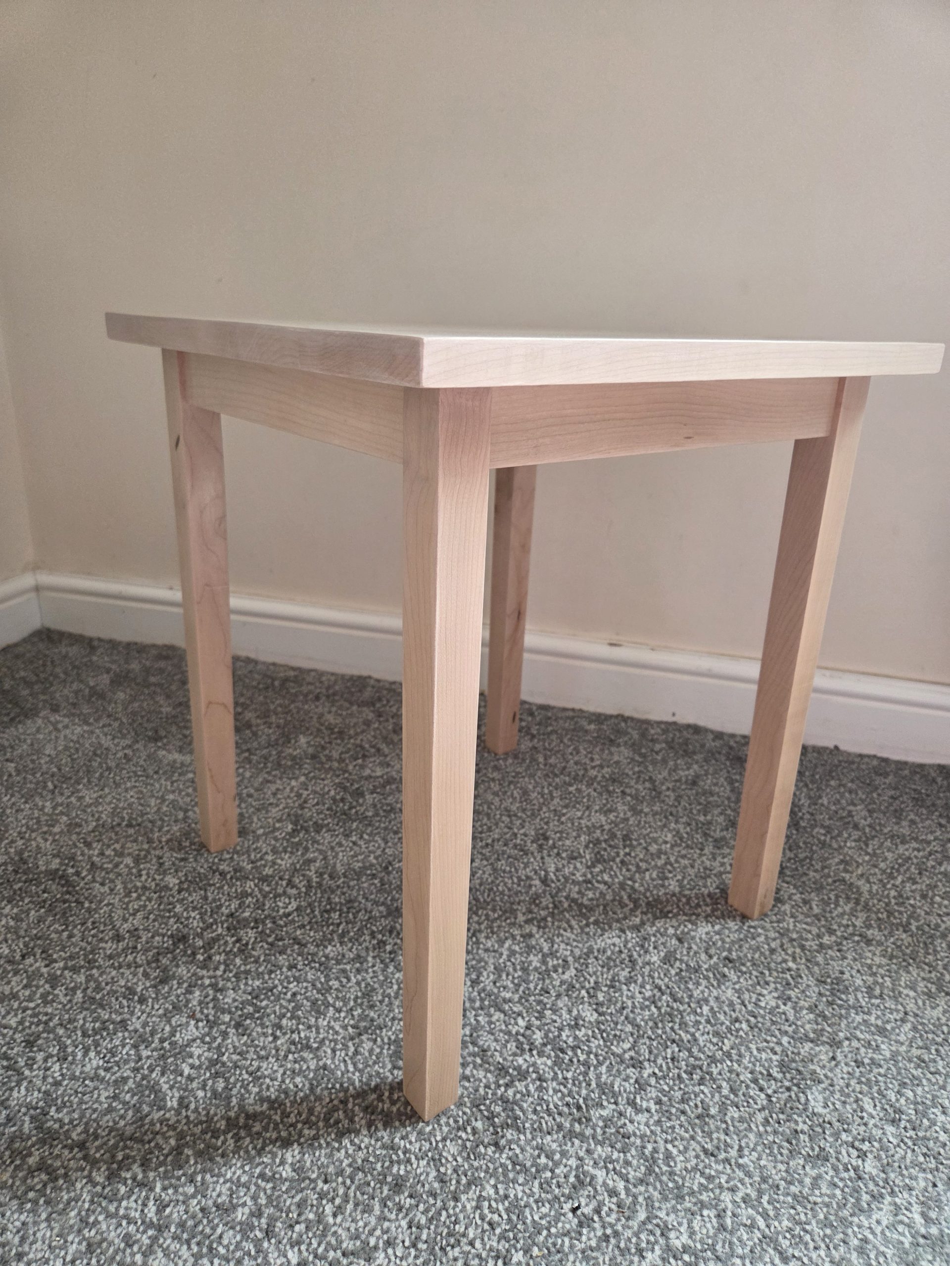 Minimalist handcrafted wooden table made from sustainably sourced light maple, designed with clean lines and a timeless four-leg structure. Photographed in a neutral interior setting to highlight the natural grain, craftsmanship, and understated elegance of the piece.