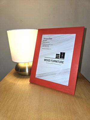 Handcrafted wooden table featuring a soft-glow lamp with a metallic base and white shade, beside a red picture frame displaying “WOOD FURNITURE BY PETER” branding. A warm, minimalist setup showcasing artisan craftsmanship and elegant home decor.