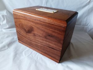 Artisan-crafted wooden ashes casket with a rich, polished finish and natural wood grain. Designed with rounded edges and a discreet brass plaque, this elegant cremation box offers a dignified, sustainable tribute made with care and craftsmanship.